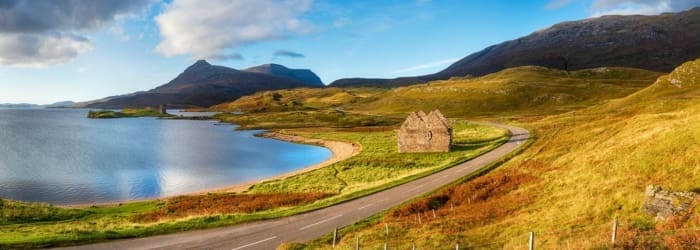 Autumn at Loch Assynt in Scotland with the ruins of Calda House and Ardvreck Castle in the far left, landmarks on the NC500 scenic driving route